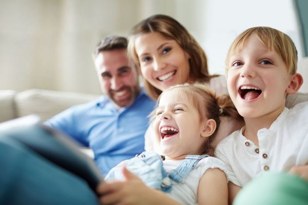 Family Dentistry: a closeup on a family of four, laughing into the camera